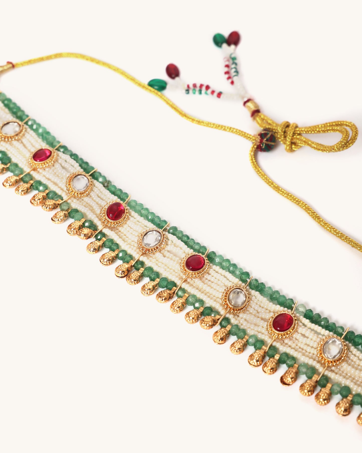 Decorative choker necklace with green beads and gold accents on a white background