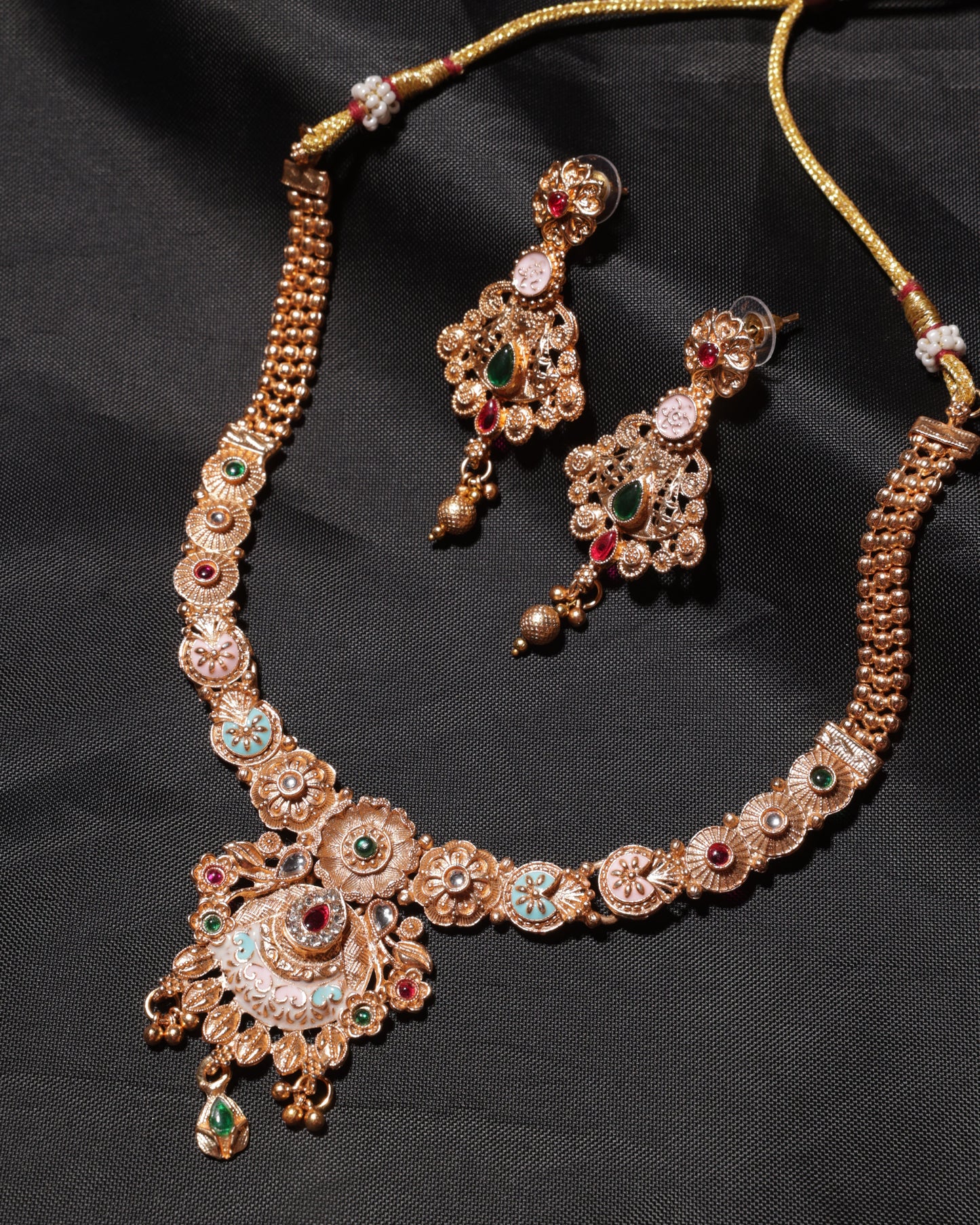 Ornate gold necklace with gemstones on a black background