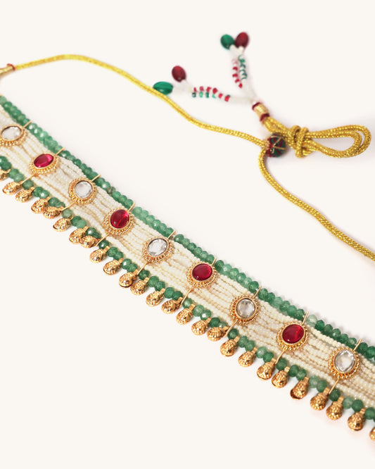 Decorative choker necklace with green beads and gold accents on a white background