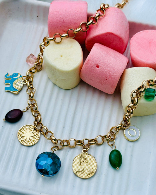 Gold bracelet with charms on a plate of colorful marshmallows